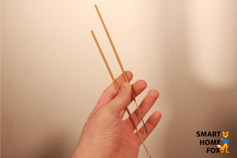 Zwei Räucherstäbchen werden in der Hand gehalten